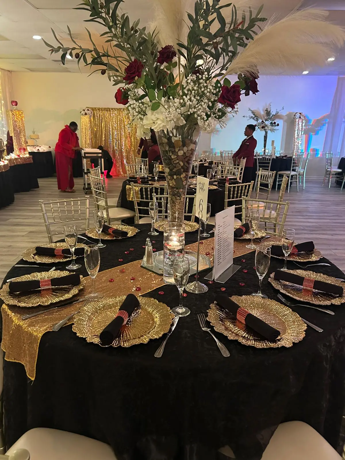 A black and gold tablescape with a tall floral centerpiece